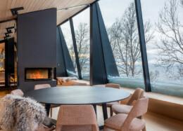 Hybridhuset Aurora Lodge 2 med stora panoramafönster och en sprakande brasa