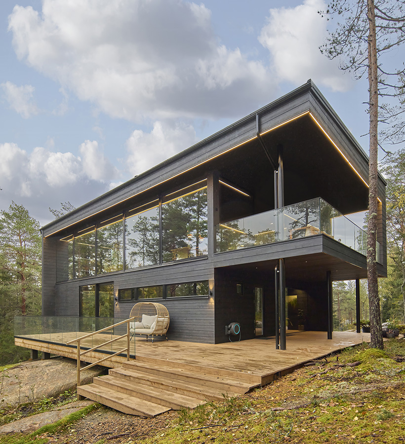 Ett modernt svart timmerhus från Polar Life Haus i skogsmiljö.